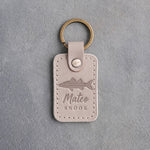 Gray Sand leather keychain debossed with a snook above Mateo and SNOOK, on gray plaster