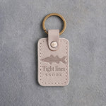 Gray Sand leather keychain debossed with a snook above Tight lines and SNOOK, on gray concrete