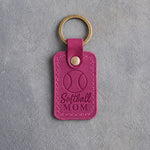 Fuchsia pink leather keychain debossed with a softball and the words Softball MOM, on gray plaster