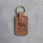 Caramel leather keychain debossed with an English bulldog silhouette and the words Sour mug SWEET HEART, on gray concrete