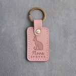 Blush pink leather keychain debossed with a sitting Sphynx cat with large ears above the name Nova and SPHYNX
