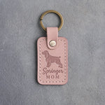 Blush pink leather keychain with a debossed springer spaniel and the words Springer MOM, on gray concrete