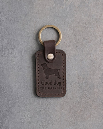 Dark espresso leather keychain debossed with a springer spaniel above Good dog and THE SPRINGER, on gray concrete