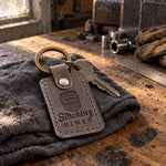 Stacking Dimes keychain in gray leather on shop keys next to a steel coupon with a rippled TIG bead