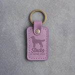 Lilac leather keychain debossed with a dog in a show stack and the words Stacks AT HOME ONLY, on gray concrete
