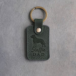 Forest green leather keychain debossed with an American Staffordshire Terrier silhouette and the words Staffie DAD, on gray concrete