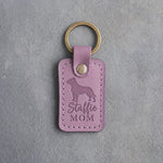 Lilac leather keychain debossed with an American Staffordshire Terrier silhouette and the words Staffie MOM, on gray concrete