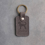 Country gray leather keychain debossed with a curly goldendoodle silhouette and the words Standing APPOINTMENT, on gray concrete