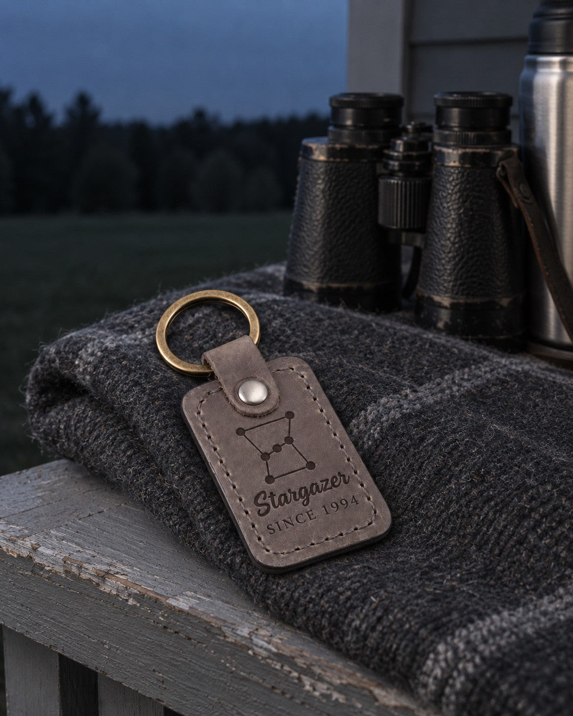 Gray Stargazer Since keychain hanging from a telescope case handle in a dark backyard lit by a red flashlight