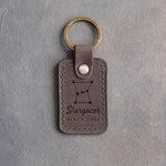 Country gray leather keychain debossed with the Orion constellation above Stargazer and SINCE 1994, on gray concrete
