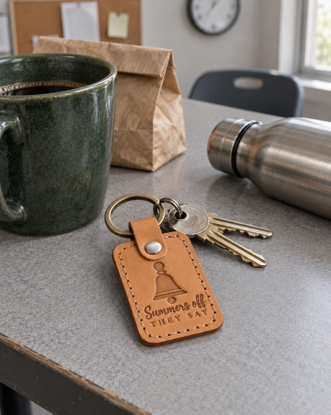 Summers Off They Say keychain in golden tan leather on a teacher's keys next to a planner open to July