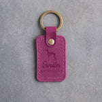 Fuchsia pink leather keychain debossed with an Italian Greyhound silhouette and the words Sweater ENTHUSIAST, on gray concrete