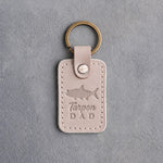 Gray sand leather keychain debossed with a tarpon above the words Tarpon DAD, on gray plaster