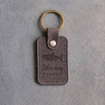 Country gray leather keychain debossed with a tarpon above Silver king and TARPON, on gray concrete