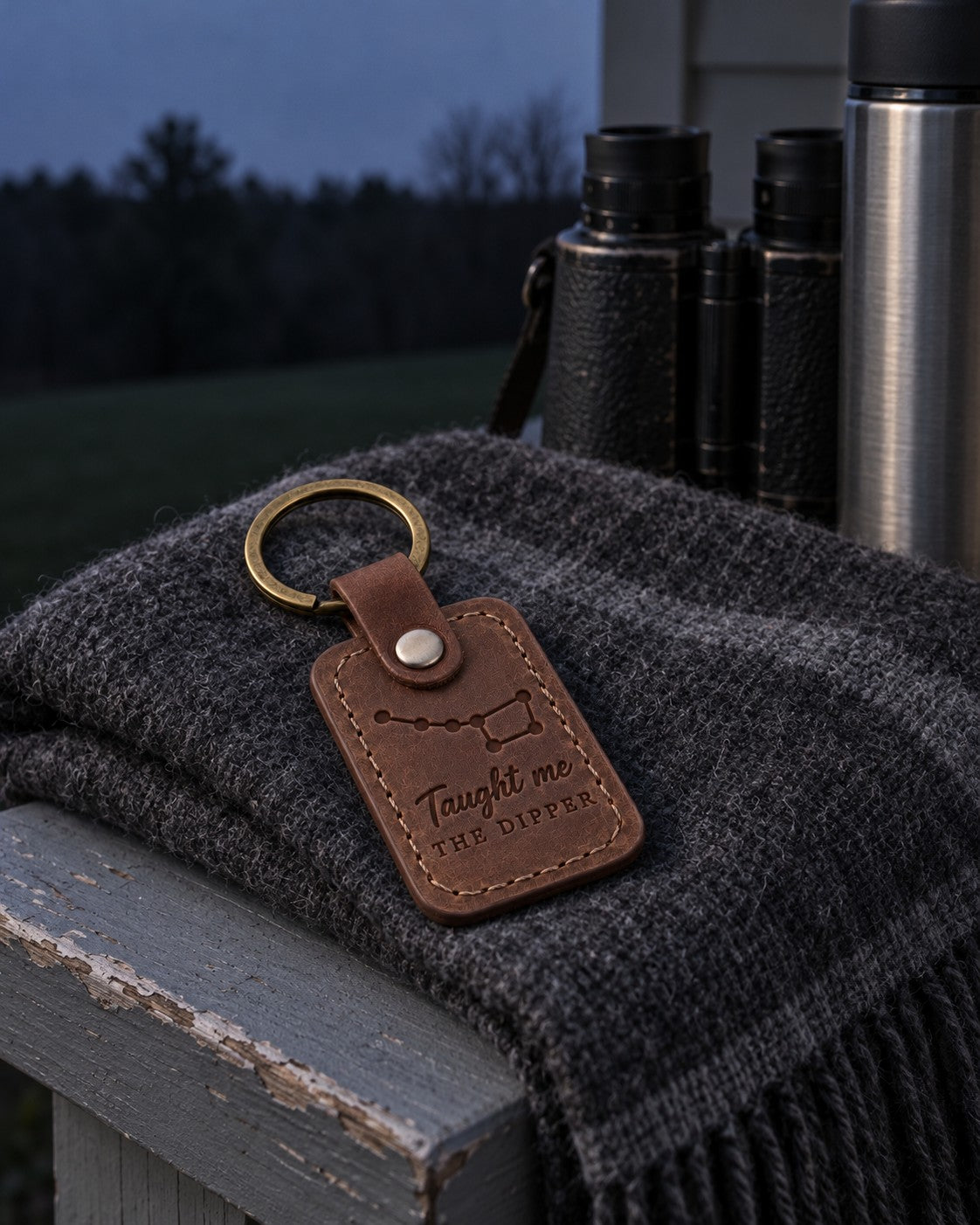 Brown Taught Me the Dipper keychain on a set of keys resting on a camp chair arm at twilight