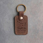 Sicilian brown leather keychain debossed with the Big Dipper above Taught me and THE DIPPER, on gray concrete