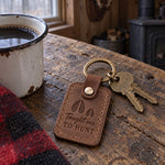 Taught Me to Hunt keychain in brown leather on an older man's key ring resting on a worn flannel shirt