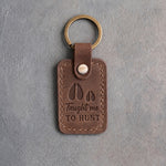 Sicilian brown leather keychain debossed with a deer track and a fawn track above the words Taught me TO HUNT, on gray plaster