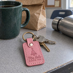 Mrs Hale Room 204 keychain in pink leather on a ring of classroom keys beside a stack of graded spelling tests