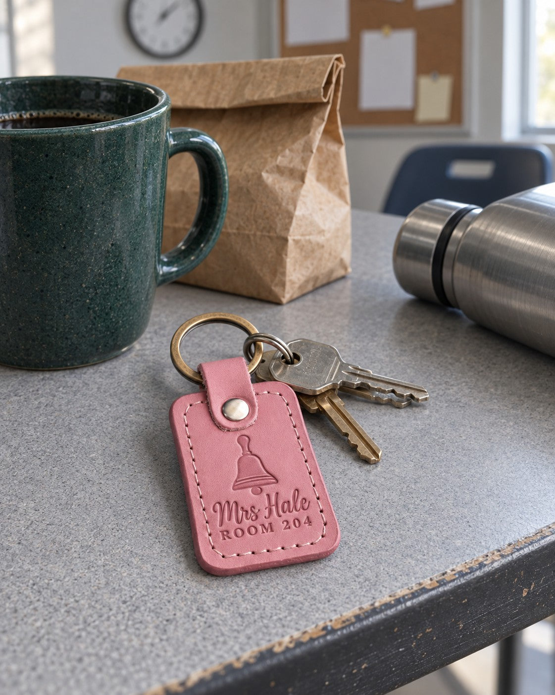 Mrs Hale Room 204 keychain in pink leather on a ring of classroom keys beside a stack of graded spelling tests