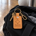 Golden brown Thanks for the Rides keychain on an open black duffel bag on a sunlit gym floor