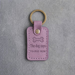 Lilac leather keychain debossed with a bone biscuit above The dog says and THANKS MOM, on gray concrete
