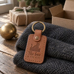 Caramel The Box Is the Gift keychain resting on top of an open cardboard shipping box