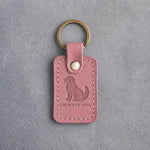 Parisian Blossom pink leather keychain debossed with a calm seated dog above THERAPY DOG, on gray concrete