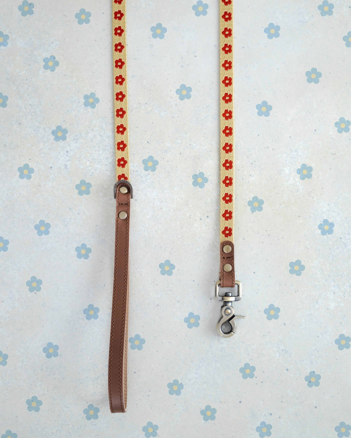 Two thin webbing leashes in cream and red hanging side by side
