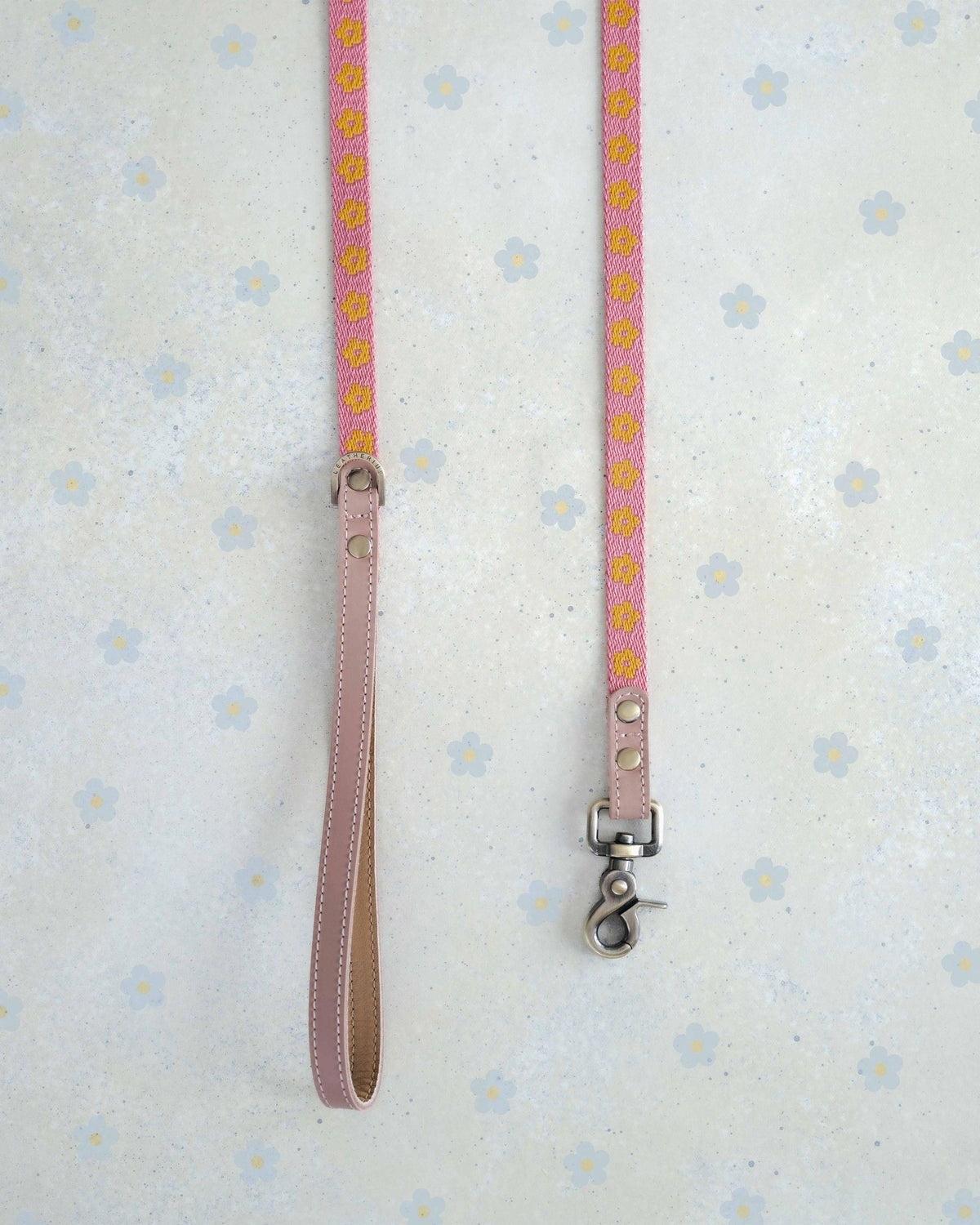 Two thin webbing leashes in pink and marigold hanging side by side