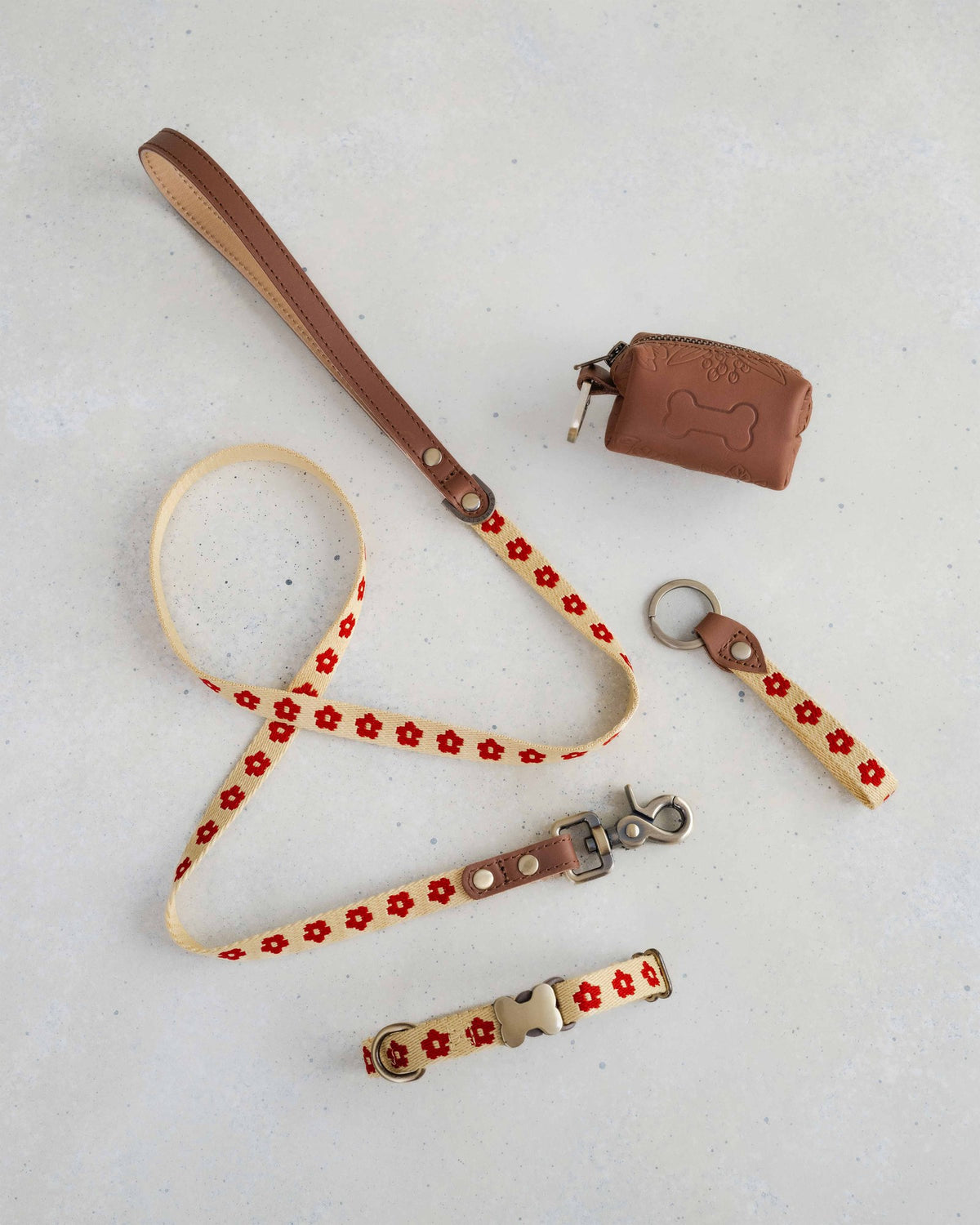 Thin webbing leash in cream and red with a matching collar, keychain and leather bag holder