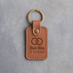 Caramel leather keychain debossed with two interlocked wedding rings above the words Year three IS LEATHER, on gray concrete