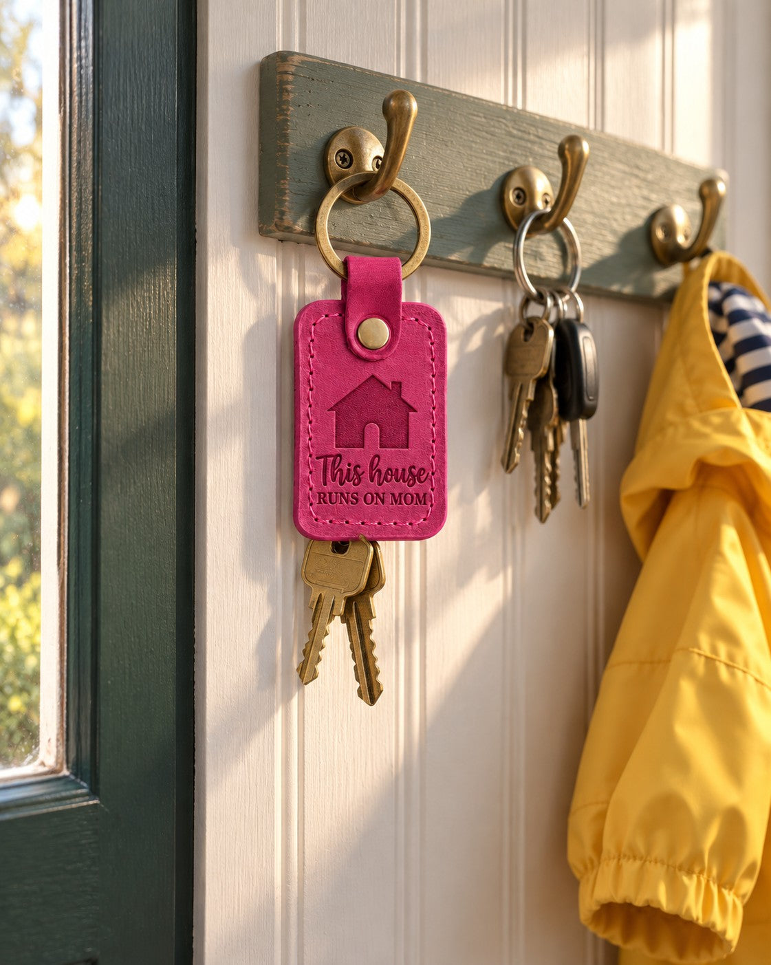 Bright pink This house RUNS ON MOM keychain on house keys beside a busy family calendar