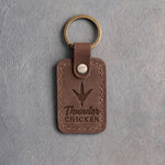 Sicilian brown leather keychain debossed with a wild turkey track above the words Thunder CHICKEN, on gray plaster