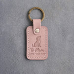 Blush pink leather keychain debossed with a dog looking up above To Mom and LOVE · THE DOG, on gray concrete