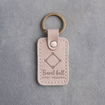 Gray sand leather keychain debossed with a baseball diamond and the words Travel ball EVERY WEEKEND, on gray plaster