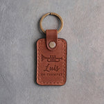 Arizona tan leather keychain debossed with a trumpet above the name Luis and ON TRUMPET, on gray plaster