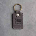 Country gray leather keychain debossed with a dachshund emerging from a tunnel and the words Tunnel VISION, on gray concrete
