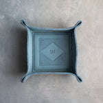 Turquoise leather valet tray with snapped corners and the initials SH pressed into the diamond frame, seen from above