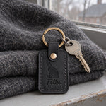 Felix TUXEDO CAT keychain in black leather on a white tablecloth under warm light