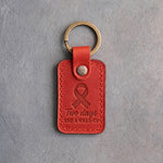 Poppy red leather keychain debossed with a looped ribbon above the words Two days AND A WAKE-UP, on gray concrete