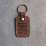 Sicilian brown leather keychain debossed with a road case above the words Unpaid ROADIE, on gray plaster