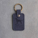 Blueberry navy leather keychain debossed with a Labrador above Thank you and VET TECH, on gray concrete
