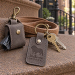 Gray Walks Are Optional keychain beside a leash left hanging on a hook by the door
