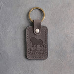 Country gray leather keychain debossed with an English bulldog and the words Walks are OPTIONAL, on gray concrete