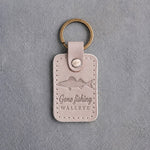 Gray sand leather keychain debossed with a walleye above Gone fishing and WALLEYE, on gray concrete