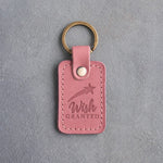 Rose pink leather keychain debossed with a shooting star above the words Wish GRANTED, on gray concrete
