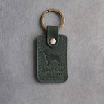 Forest green leather keychain debossed with a Boykin spaniel and the words Won't rock THE BOAT, on gray concrete
