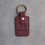 Sangria red leather keychain debossed with a Shar Pei silhouette and the words Wrinkles FOR DAYS, on gray concrete