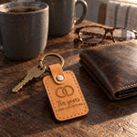 Ten years AND COUNTING keychain in golden tan leather on an oak kitchen table beside reading glasses and a mug